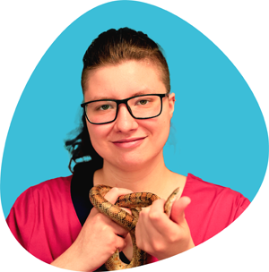 Photo d'une assistante vétérinaire portant une blouse rose, caressant un chien, devant un fond orange